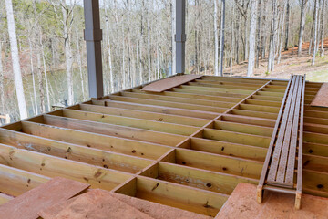 An newly constructed layout of flooring joists inside new custom built home with wooden deck patio
