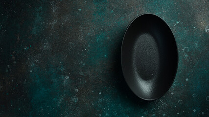 Oval slate black plate. On a dark green-turquoise background. Free space for text.