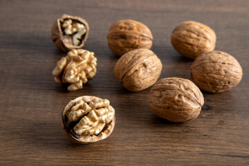 Peeled walnuts and whole walnuts in wooden table
