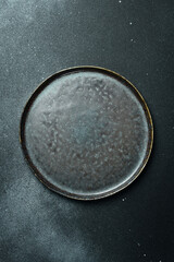 Empty gray plate (ceramic) on a dark gray background. Free space for text. Top view.