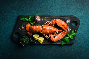 Top view of whole red lobster with lemon, basil and spices. Free space for text.
