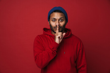 Indian man showing silence gesture isolated over red background