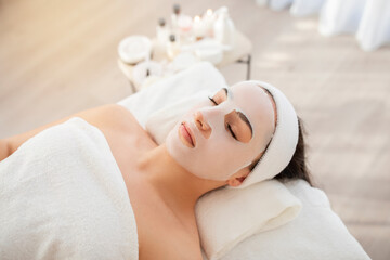 Fototapeta na wymiar Beauty Treatment. Woman With Sheet Mask On Face Relaxing At Spa Salon