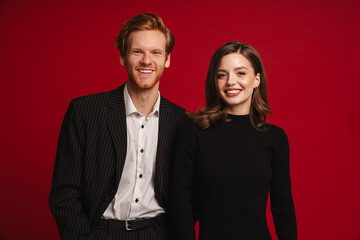 Beautiful couple posing isolated over red wall