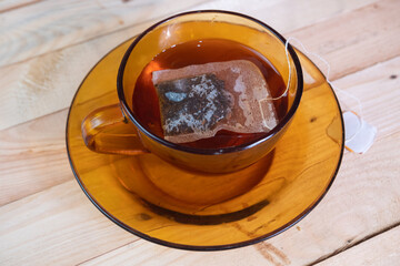 selective focus on a teabag in glass on wooden table. soft focus