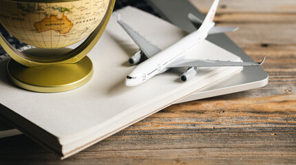 Travel composition with a model of an airplane and a globe on a wooden table.