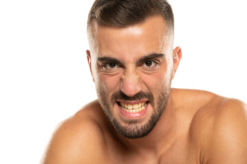 portrait of young angry shirtless man with beard, screaming on a white background