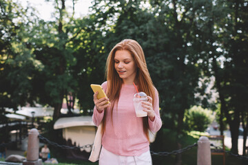 Smiling woman standing with smartphone in park