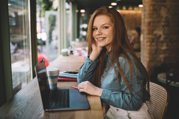 Smiling woman sitting at table with laptop in cafe