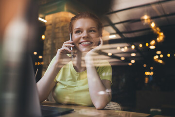 Smiling woman speaking on smartphone in cafe