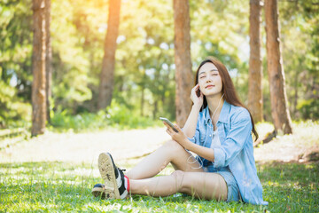 Woman freelance Lifestyle listening to music in headphones sitting in the park on the grass