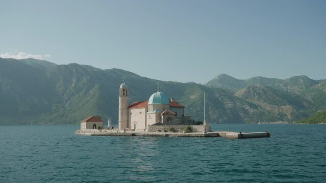 Castle orthodox church on Island on the lake in Montenegro. Adriatic Sea yacht travel cruise during summer vacation. Leligion, architecture concept. Kotor cathedral village ruins. Lonely temple pier