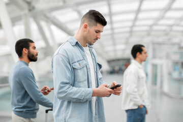 Man Using Smartphone Standing With Other Passengers In Modern Airport