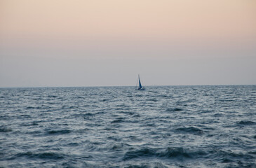 Fototapeta premium Lonely boat at sea, sailboat in the distance on the high seas