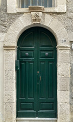 Fototapeta na wymiar 18th century intricately hand-carved, dark green wooden door & archway in Sicily.