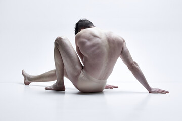 Anonymous. Image of shirtless man with relief, strong body, back posing in underwear against white studio background. Concept of male body aesthetics, men's beauty, inspiration, health, strength