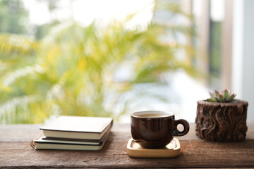 coffee cup and cactus in a pot on wooden table with notebooks