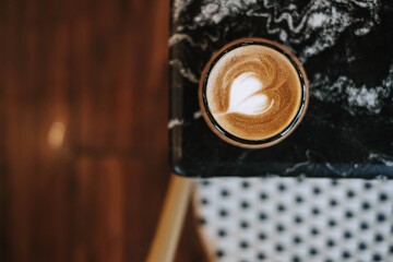 Flat lay or top view shot of a cup of coffee with beautiful and simple Latte Art on black marble table