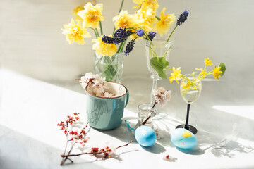 Easter concept. Various spring flowers and colored Easter eggs. Delicate light photo with soft artistic focus