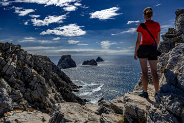 Young Woman Stand At The Edge Of The Cliffs At Pointe De Penhir At The Finistere Atlantic Coast in...