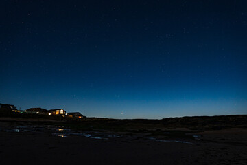 A moonlit view of the night sky over the beach at Beadnell , Northumberland in the United Kingdom.