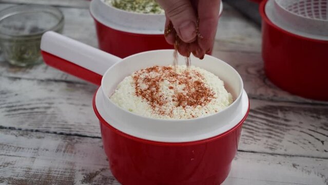 Making homemade adyghe cheese in the cheese making mold. Sprinkling the hot product with smoked paprika 