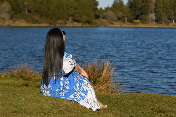 Une femme assise au bord d'un lac en été