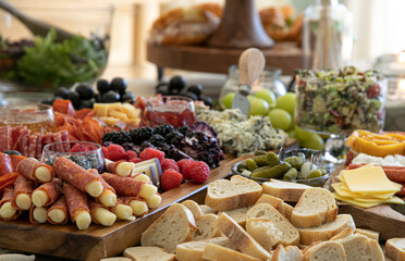 Beautiful charcuterie table set up for lunch with meats, cheeses, sandwiches, and vegetables.