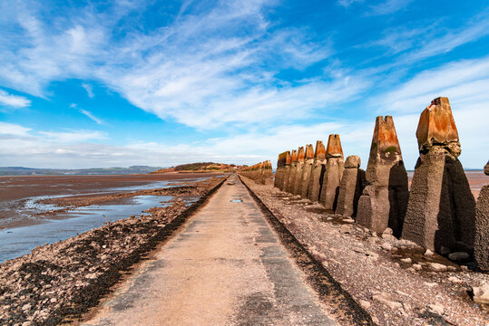 Camino hacia la isla de Cramond en Edimburgo, Escocia, queda al descubierto al bajar la marea. A un lado, aparece una barricada antitanque de la Segunda Guerra Mundial. Día de verano. 