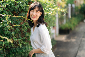 Portrait beautiful young asian woman happiness standing aside green plant wall, Happy female is smiling aside green plant wall, wellness people concept.
