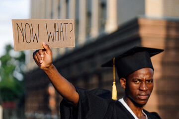 Portrait closeup of black guy holding in hand upraised cardboard poster on street looking for job,...