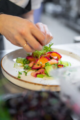 Chef cooking Green salad with salmon, cucumbers, lettuce, spices, caviar on restaurant kitchen