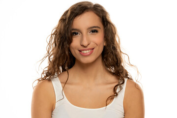 Portrait of a young smiling woman with makeup and long wavy hair on a white studio background