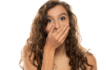 young beautiful girl covering her mouth with her hands for joy on a white background
