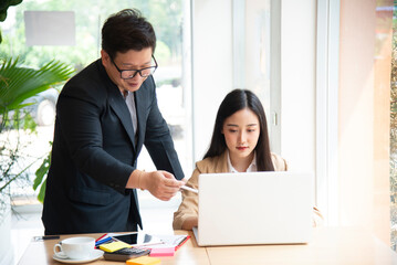 Asian businessman and businesswoman discussing new business project in tablet in modern Meeting In Modern Office, business casual concept.