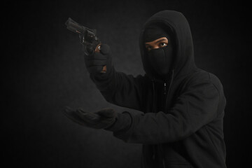 The male thief forcibly demanded the victim's money and valuables at gunpoint