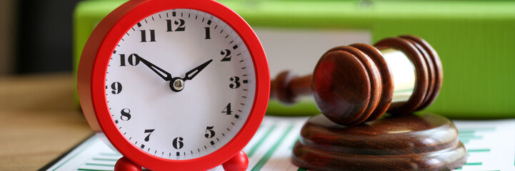 Judges gavel with alarm clock on financial documents