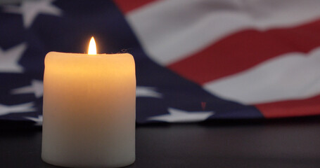 A burning candle on the background of the flag of the United States. Background of grief, memories or celebrations