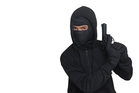 Mysterious man wearing black hoodie and mask holding a pistol, shooting with a gun. Isolated image on gray background