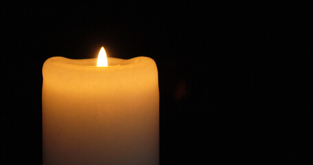 A burning insulated candle on a dark background.