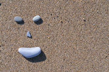 Fototapeta na wymiar Cara sonriente con piedras sobre la arena de una playa