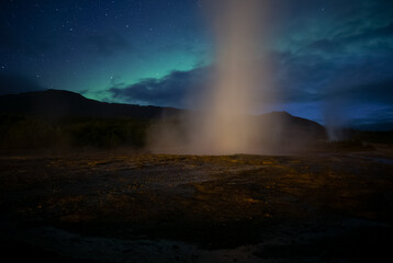 Geyser erupting in front of Aurora borealis, Geysir Iceland