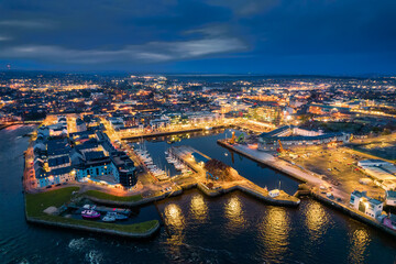 Illuminated port town at night. Aerial view on River Corrib and Galway city, Ireland. Dark sky....