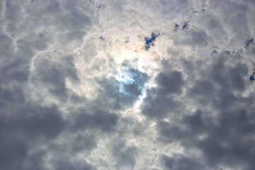 Dark contrasting sky with clouds and the contour of the sun behind the clouds
