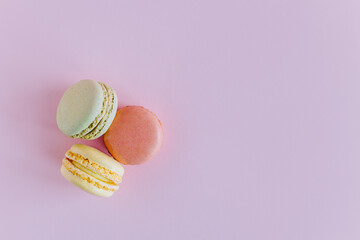 Tasty french macarons on a pink pastel background.