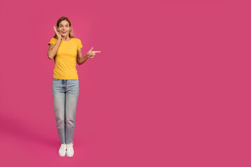 Shocked cheerful middle aged european blonde female pointing finger at free space