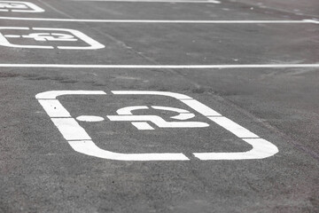 Parking lot with white painted handicapped symbol of wheelchair on asphalt, parking spaces for disabled visitors. Empty disabled parking space. Free parking sign for disabled people's car.