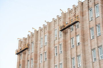 Builders on the upper floors paint and restore the facade of a multi-storey house