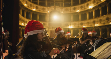 Cinematic Shot of Symphony Orchestra Musicians Wearing Santa Hats and Performing on the Stage of a...