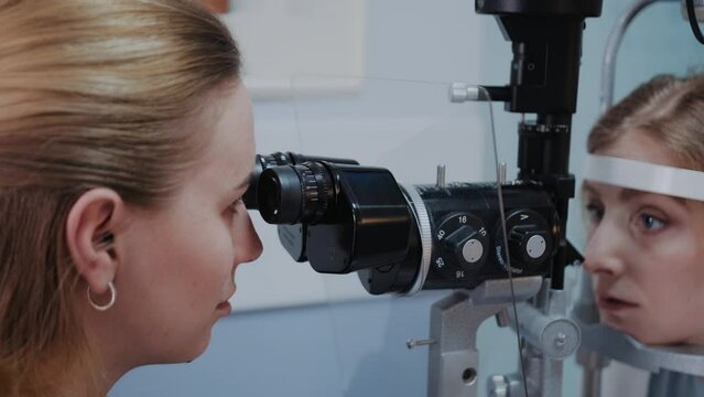 Optometrist examining the eyesight of woman with a slit lamp